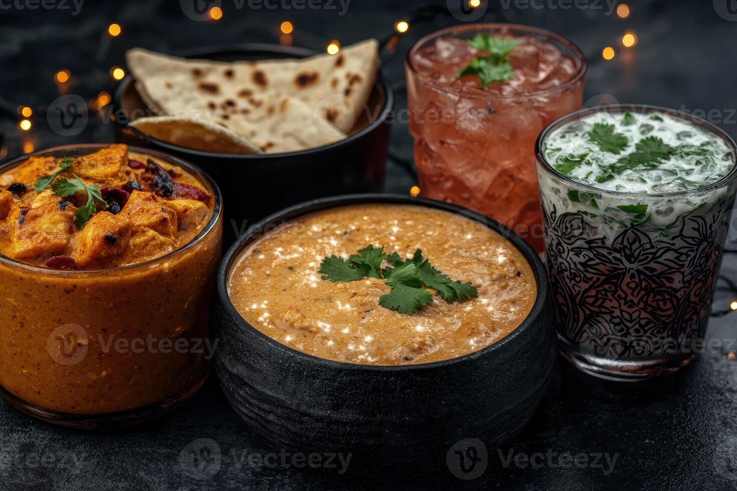 A spread of Indian food with curry, naan, and drinks photo