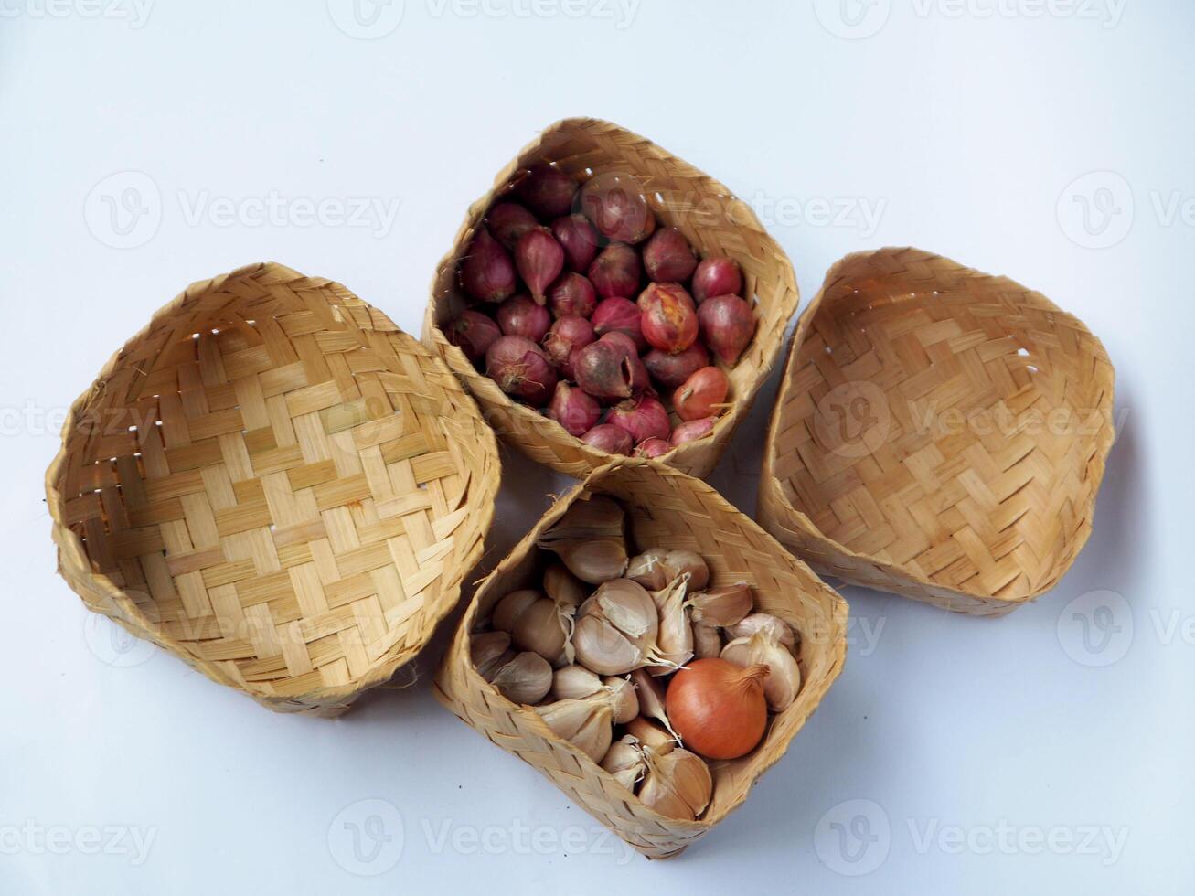 Wicker baskets containing garlic and shallots are artistically displayed with an on a white surface, showcasing rustic kitchen elements and traditional food presentation for culinary themes. photo
