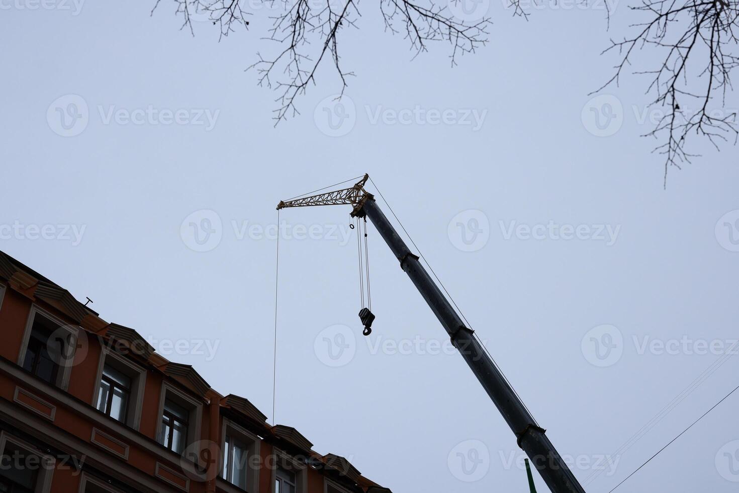 A Construction Crane is Actively Working Near a Building in an Urban Setting Today photo