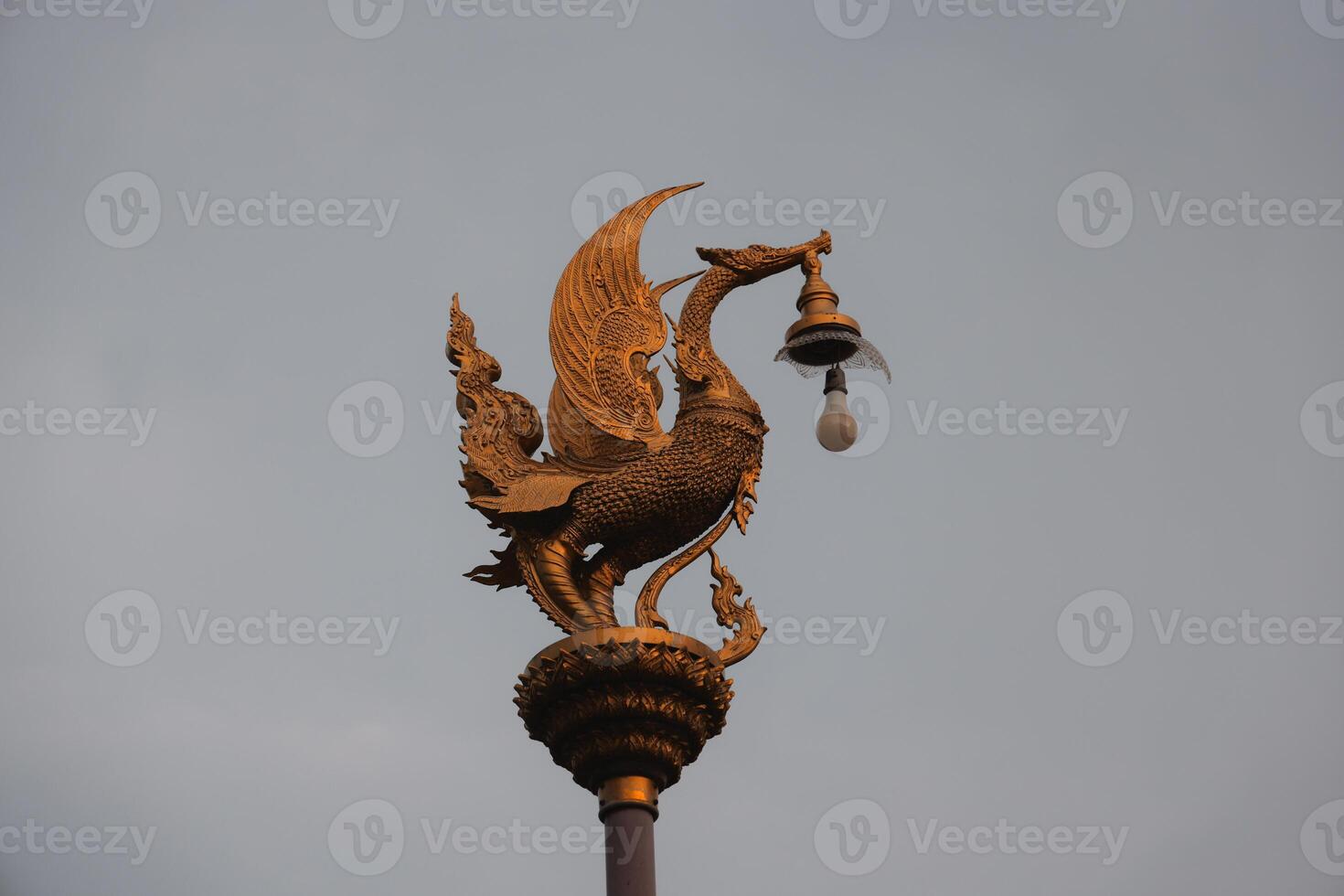 A stunning Golden Mythical Creature with a Bell atop a tall Pole, highlighting creativity photo