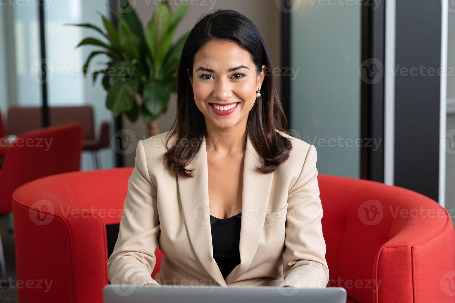 A woman in a business suit sitting at a table with a laptop photo