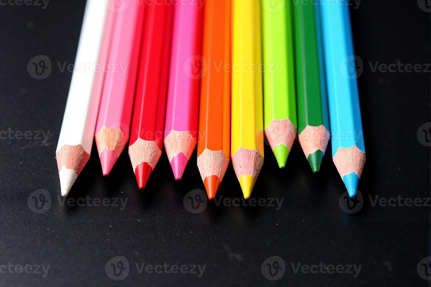 A group of colored pencils on a black surface photo