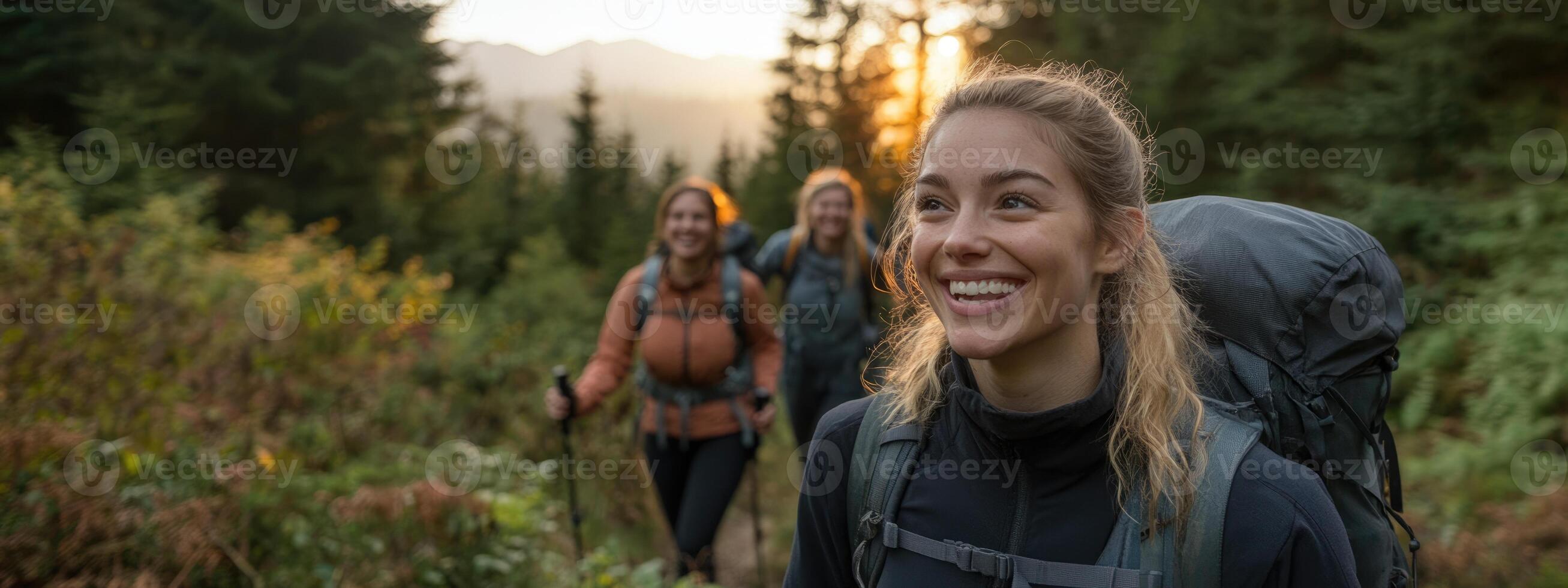 A group of friends embarks on an adventurous hike through a forested area during sunset. The lead hiker smiles, revealing joy and camaraderie as they explore nature together photo