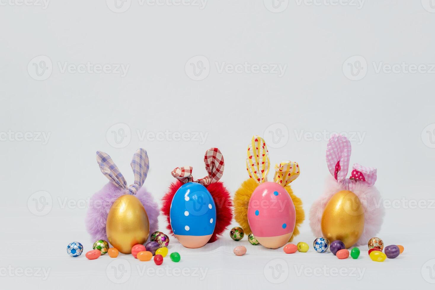 Colorful Easter eggs and bright pink and white flowers with a representation of a bunny on a white table on a white wall background photo