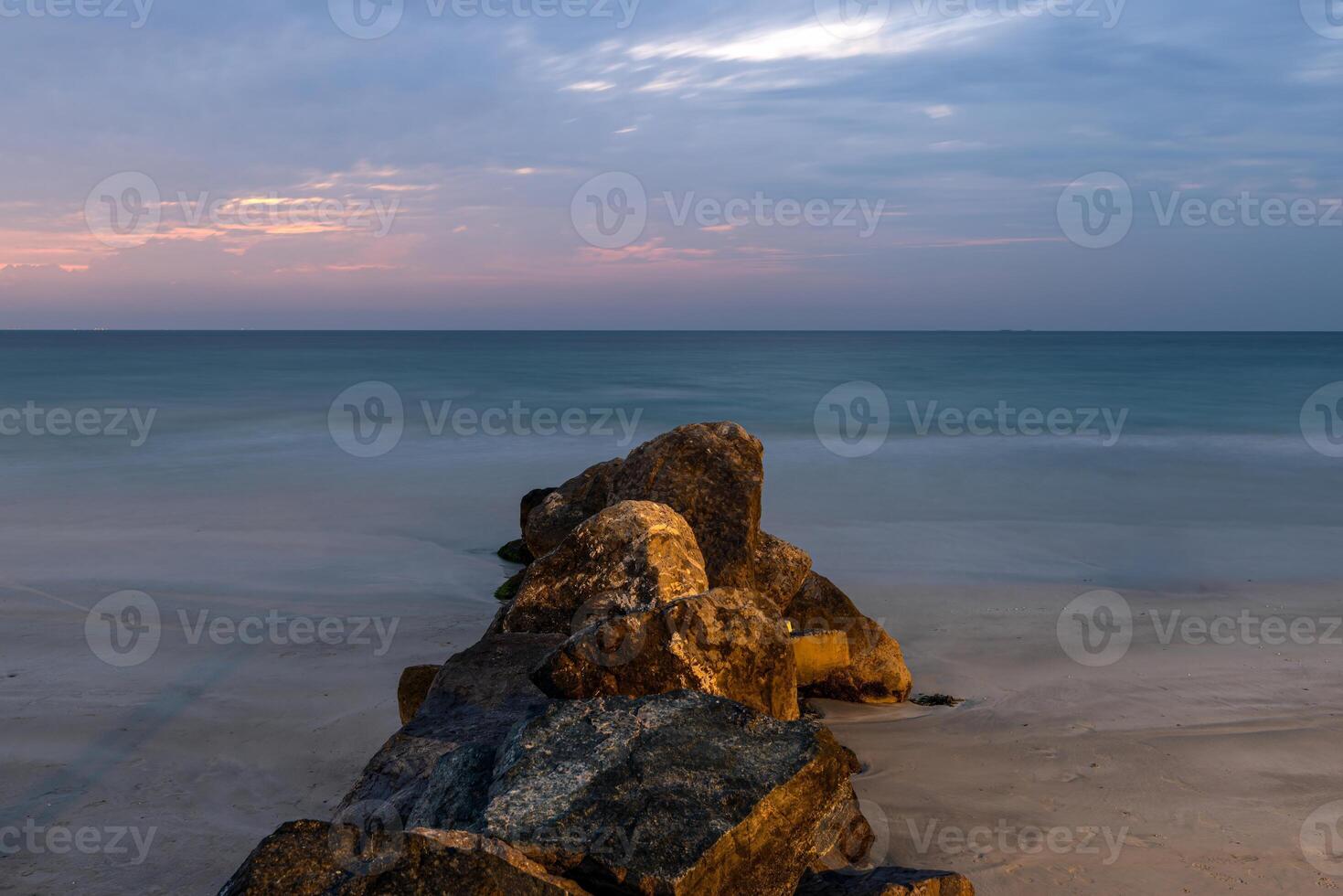 A wave breaker made of rocks illuminated by warm evening light photo
