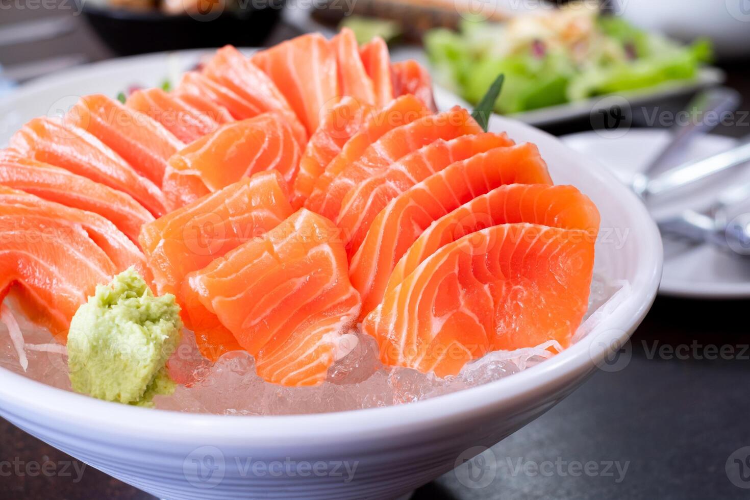 Raw salmon slice or salmon sashimi and wasabi in Japanese style fresh serve on ice in white bowl. Japanese traditional food or with low calories and high nutrition and healthy diet dish. photo