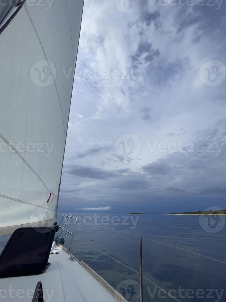 a sailboat with a white sail and cloudy sky photo