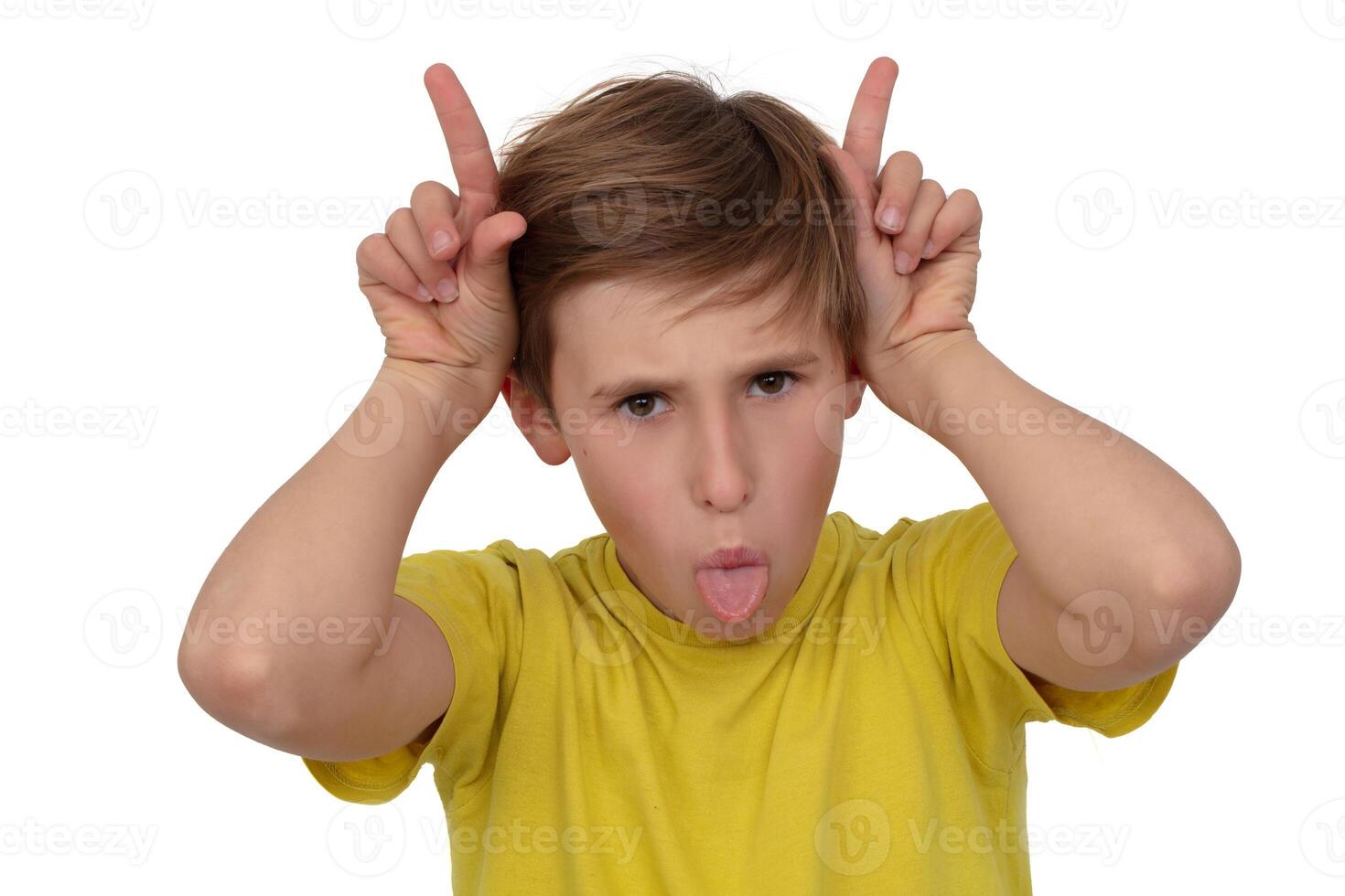 Portrait of a funny boy, he grimaces, shows his tongue and makes horns with his fingers. photo