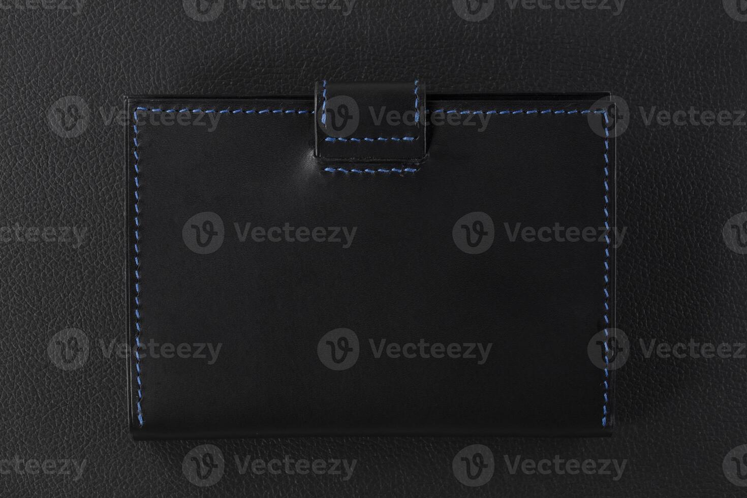 Black leather wallet with blue stitching on a black background photo