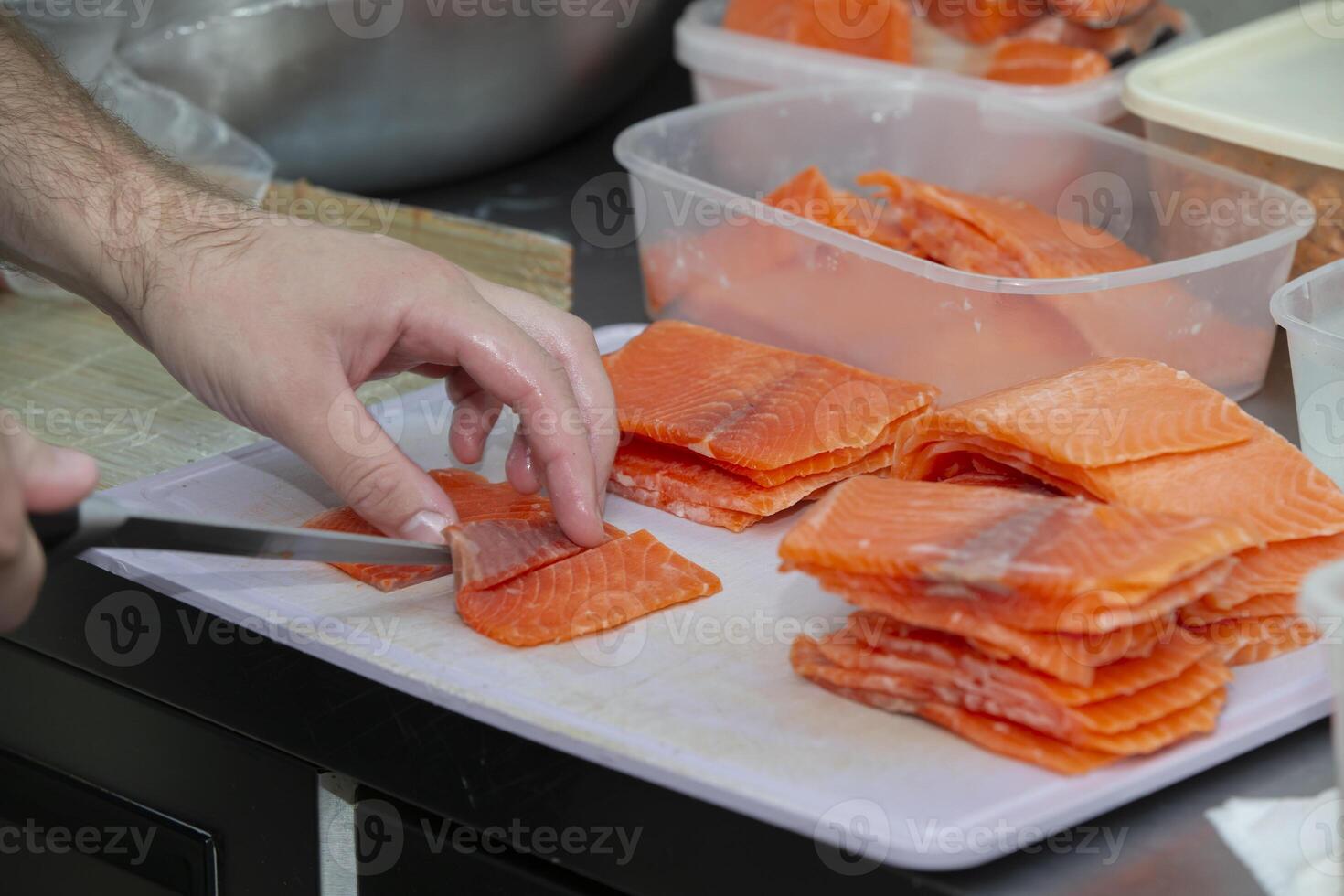 Human hands are slicing red fish with a knife. photo