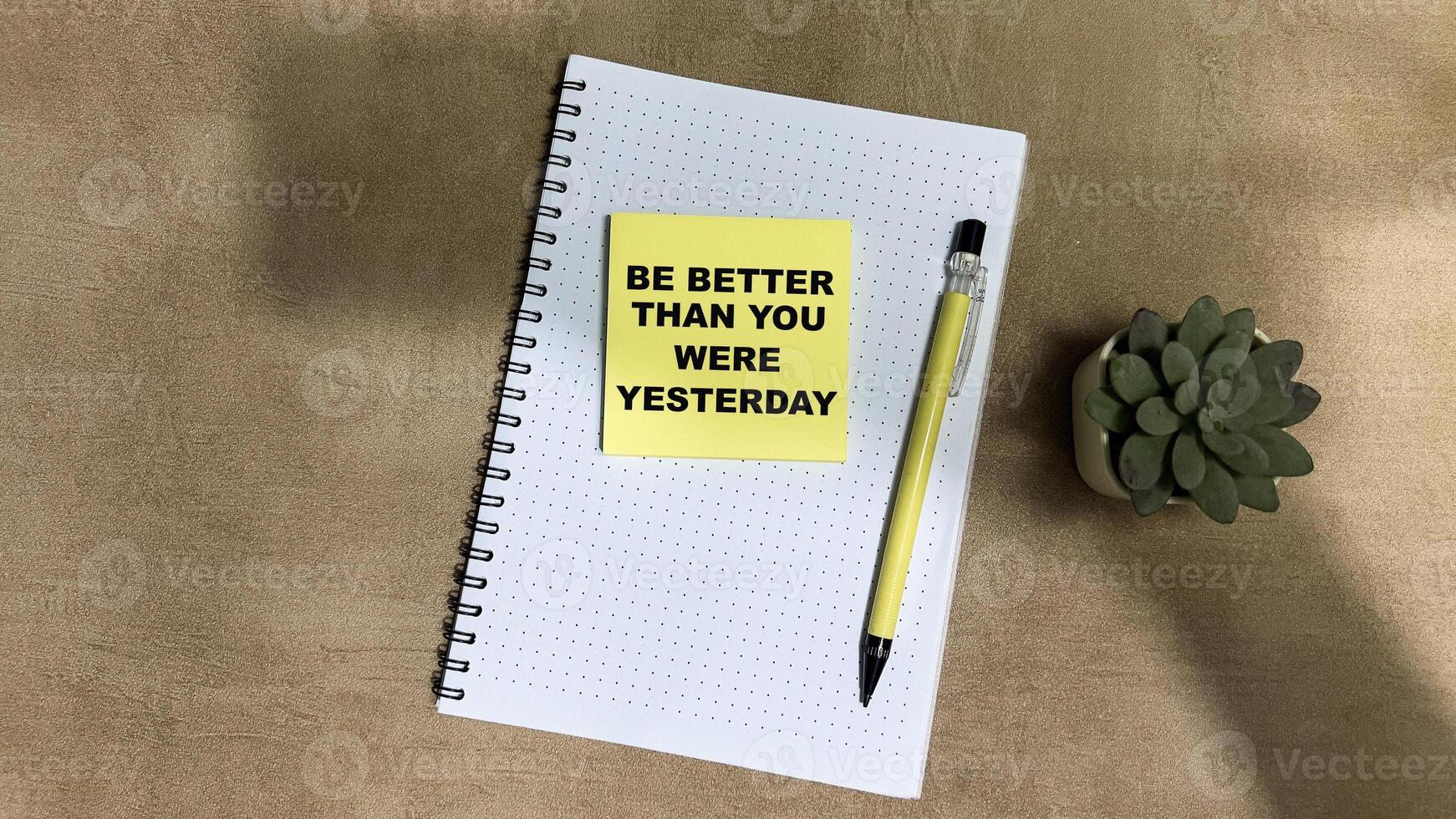 Concept of Be Better Than You Were Yesterday write on sticky notes isolated on Wooden Table. photo
