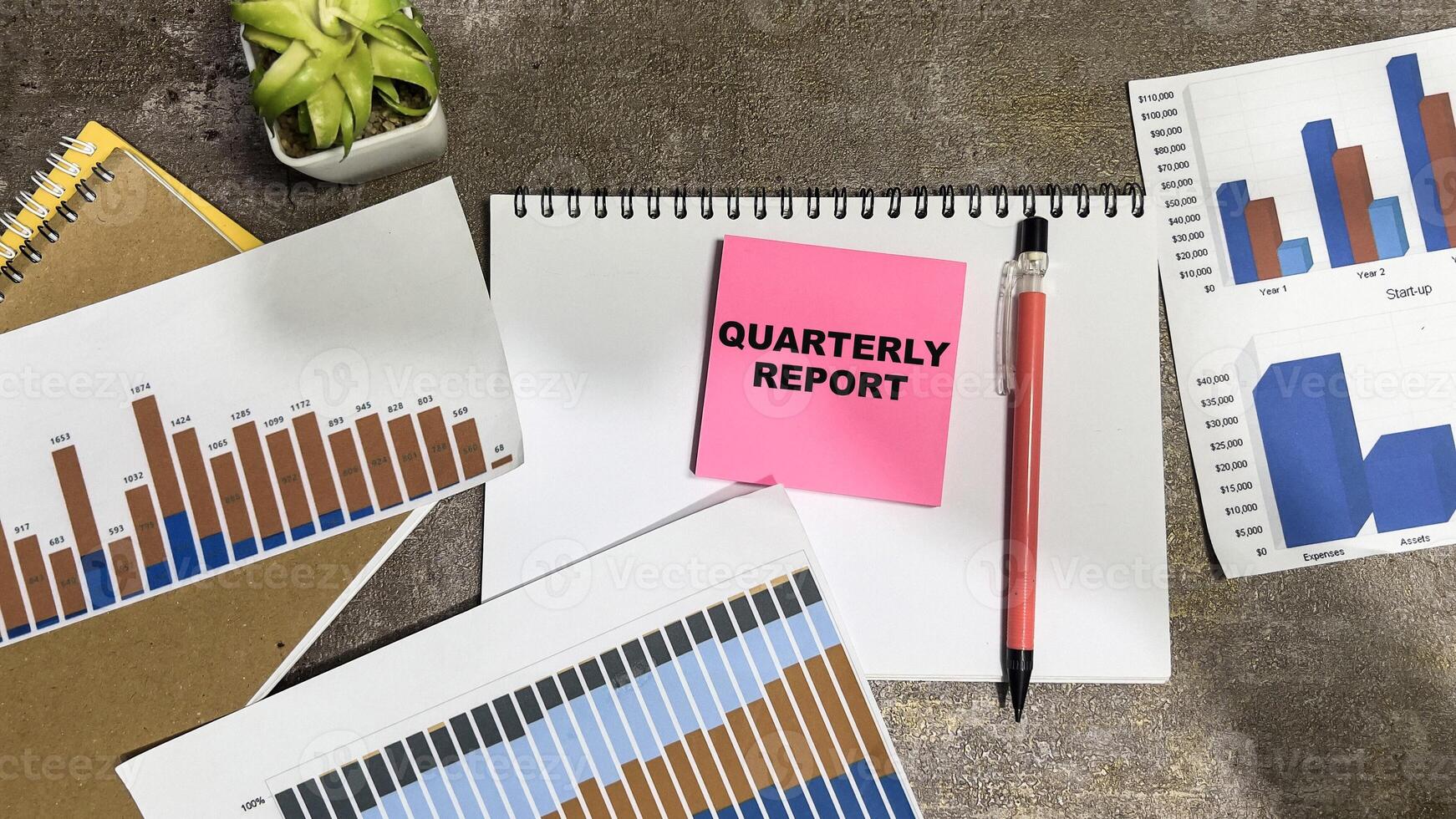 Concept of Quarterly Report write on sticky notes isolated on Wooden Table. photo