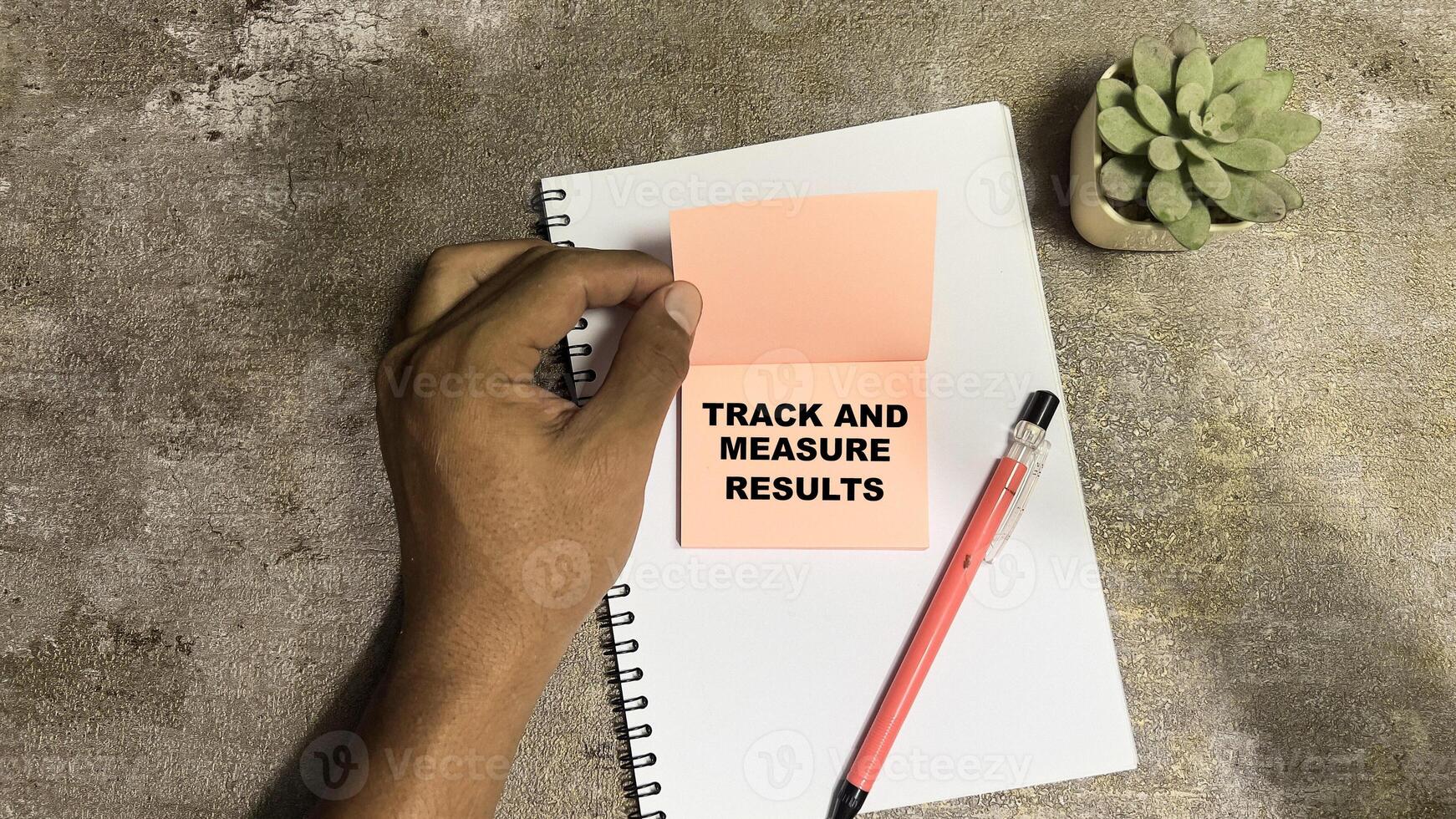 Concept of Track and Measure Results write on sticky notes isolated on Wooden Table. photo