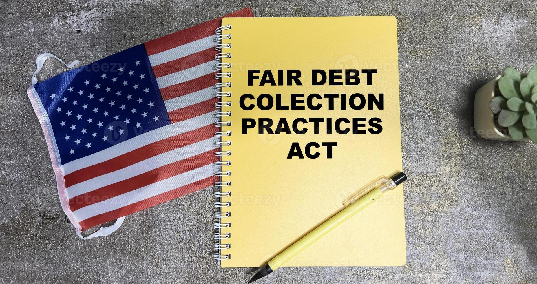 Concept of Fair Debt Collection Practices Act write on book and Flag of the United States isolated on Wooden Table. photo