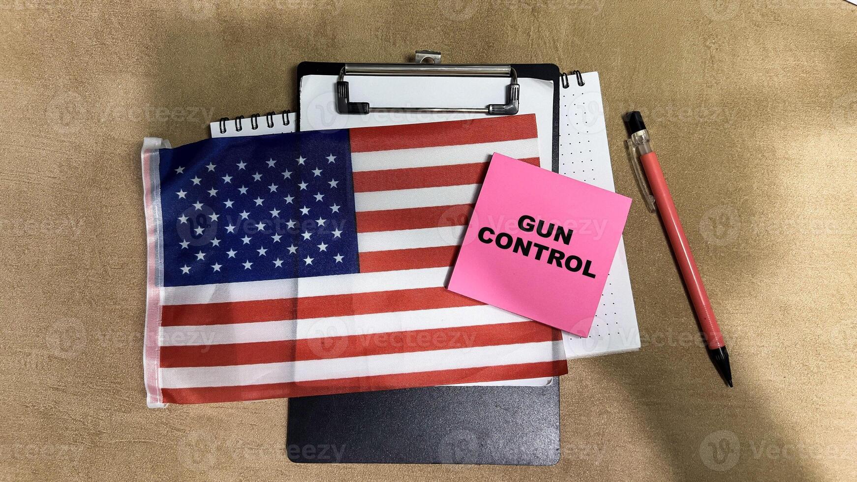 Concept of Gun Control write on sticky notes and Flag of the United States isolated on Wooden Table. photo