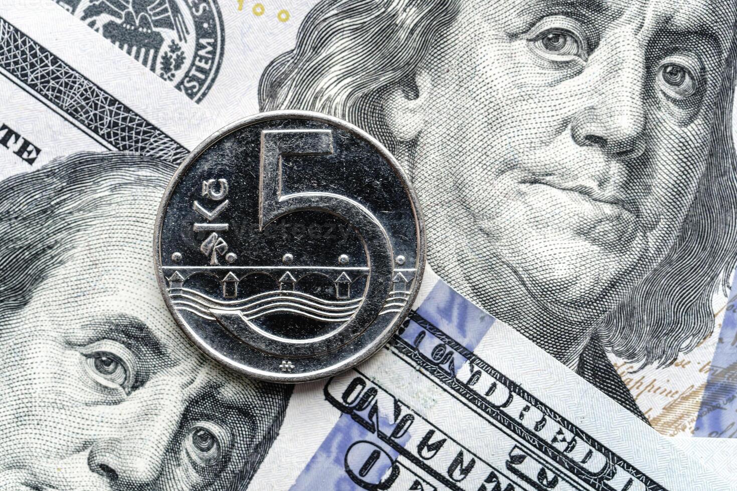 A five dollar coin is sitting on top of a stack of us dollars photo