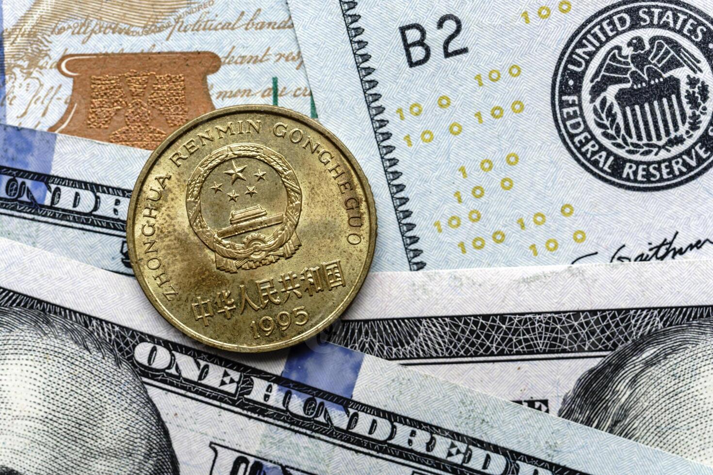 A one dollar coin is sitting on top of a hundred dollar bill photo