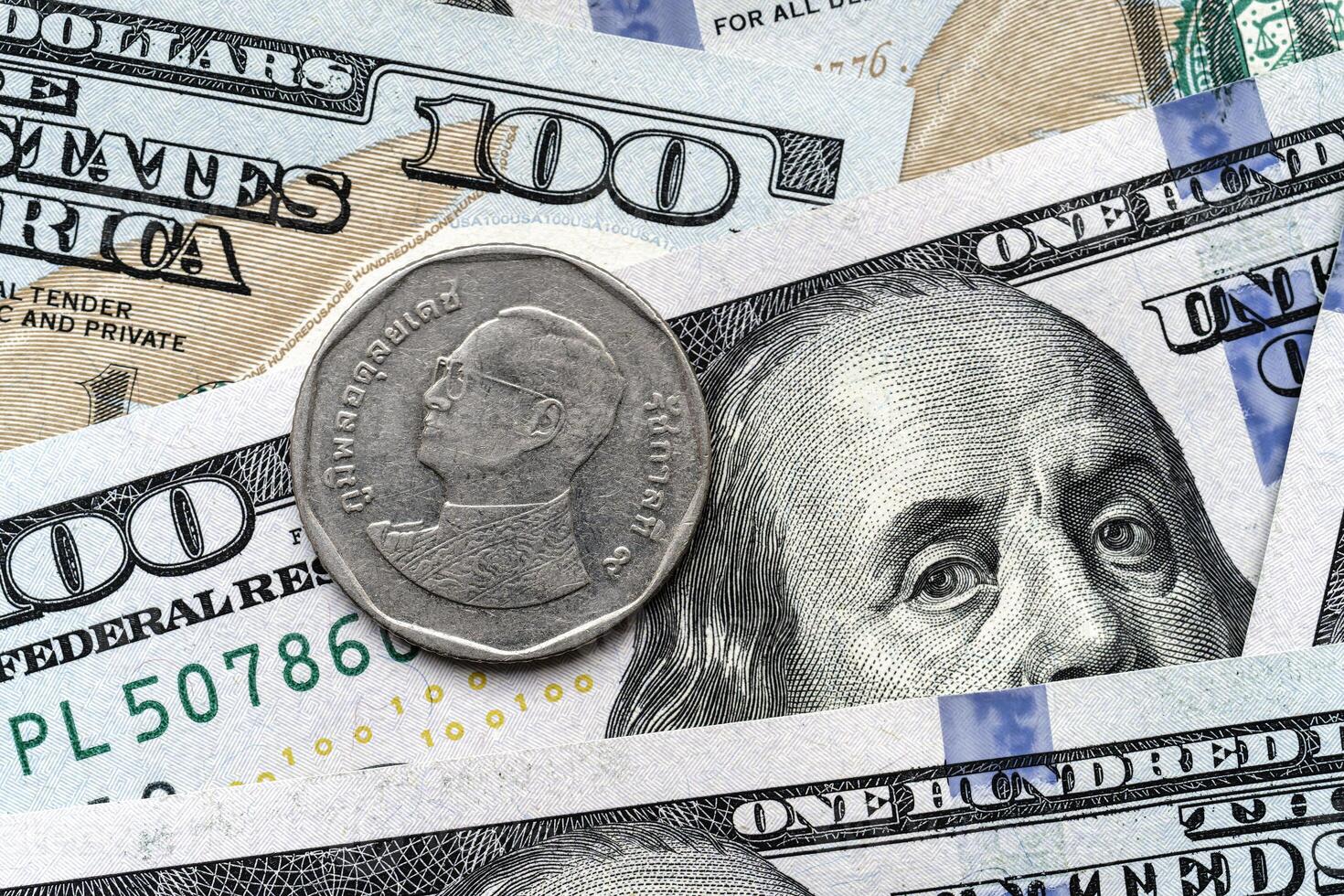 A one dollar coin is sitting on top of a pile of us dollars photo