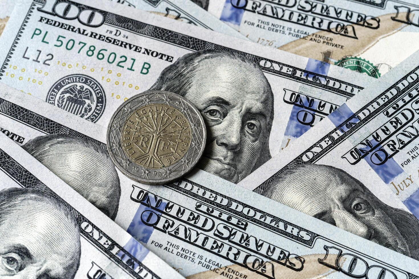 A close up of a one dollar coin on top of a stack of us dollars photo