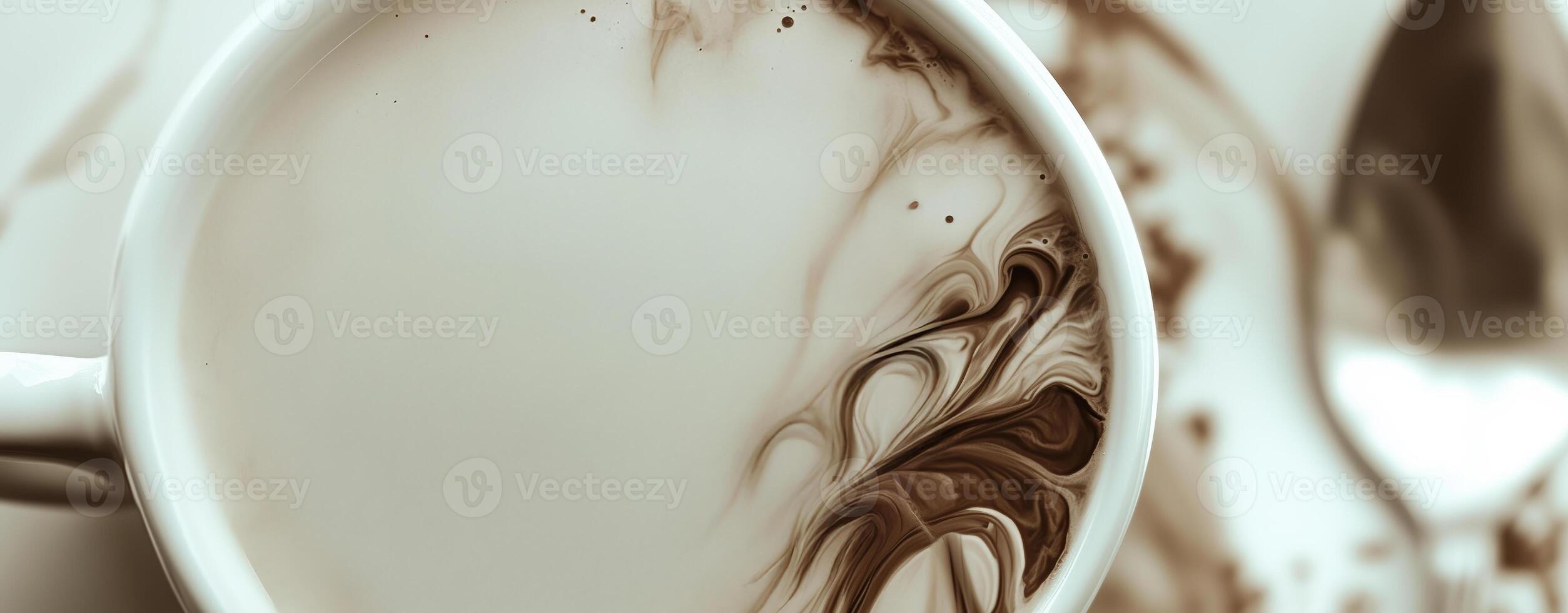 Swirling coffee patterns in a white cup and saucer with a spoon beside it on a table photo