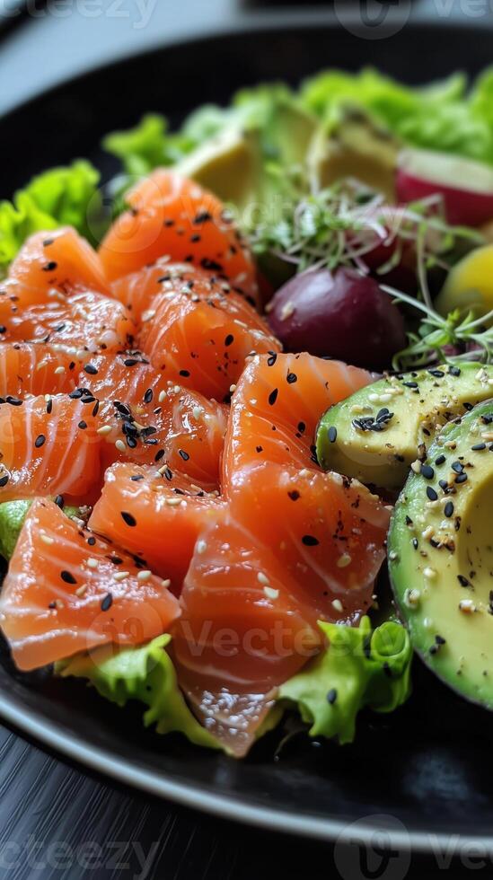 Fresh sashimi and avocado salad with greens and sesame seeds. A mix of ingredients on a black plate photo