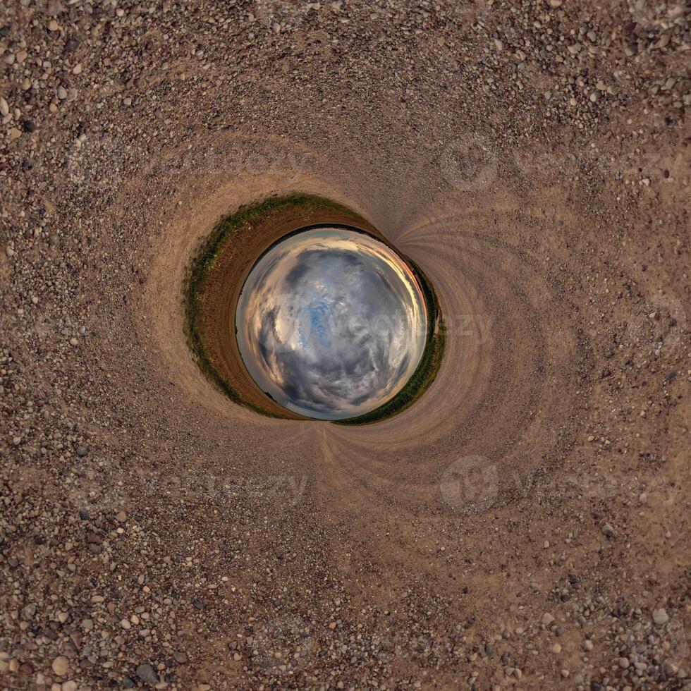A circular hole in the ground with a sky in the middle photo