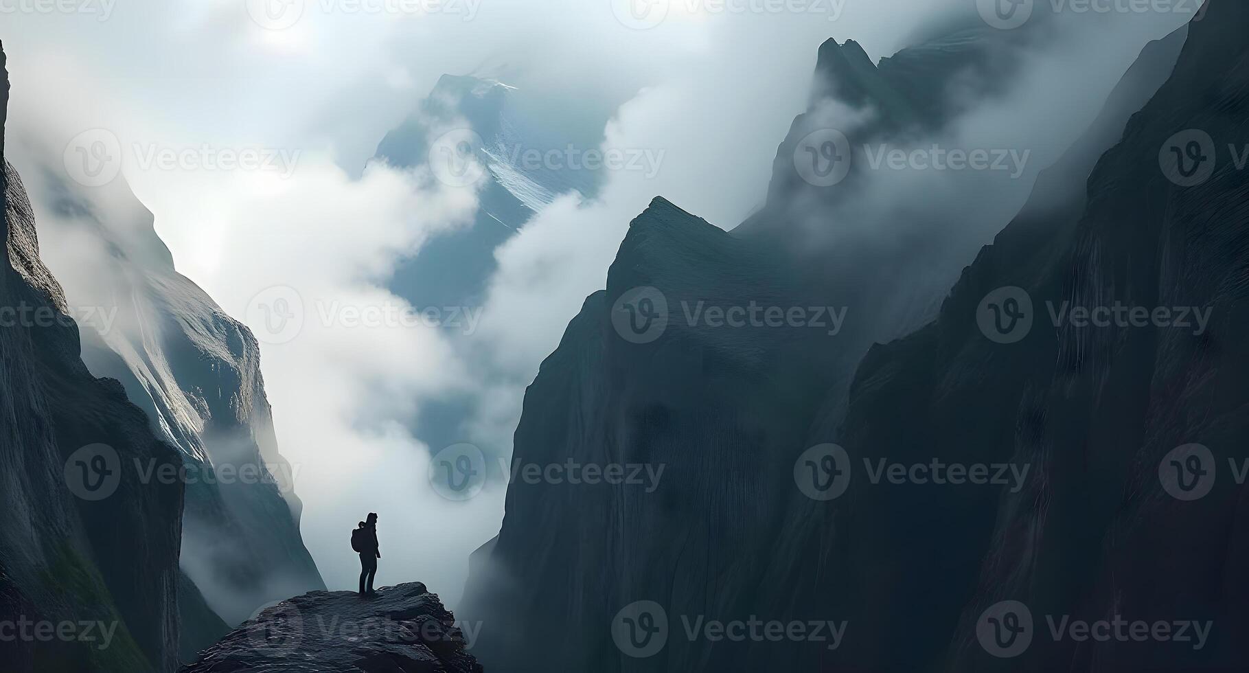 A man standing on a cliff looking at the mountains photo