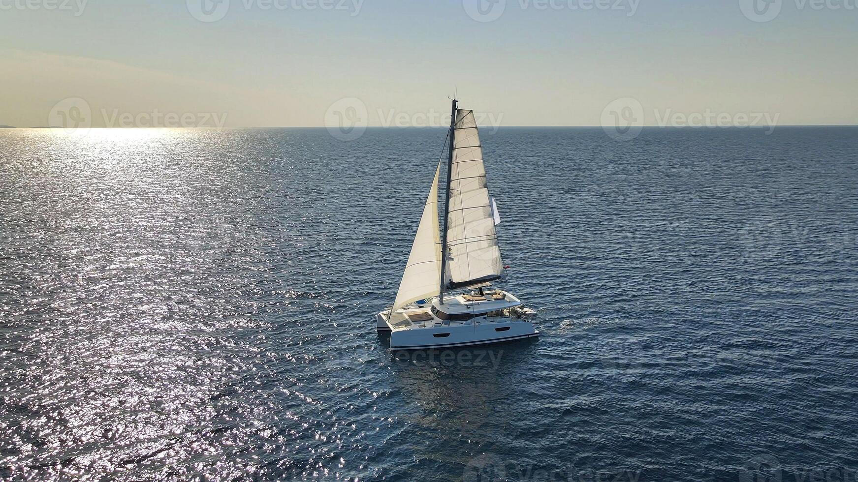 Catamaran Yacht Under Sail Moving On Open Sea At Sunset photo