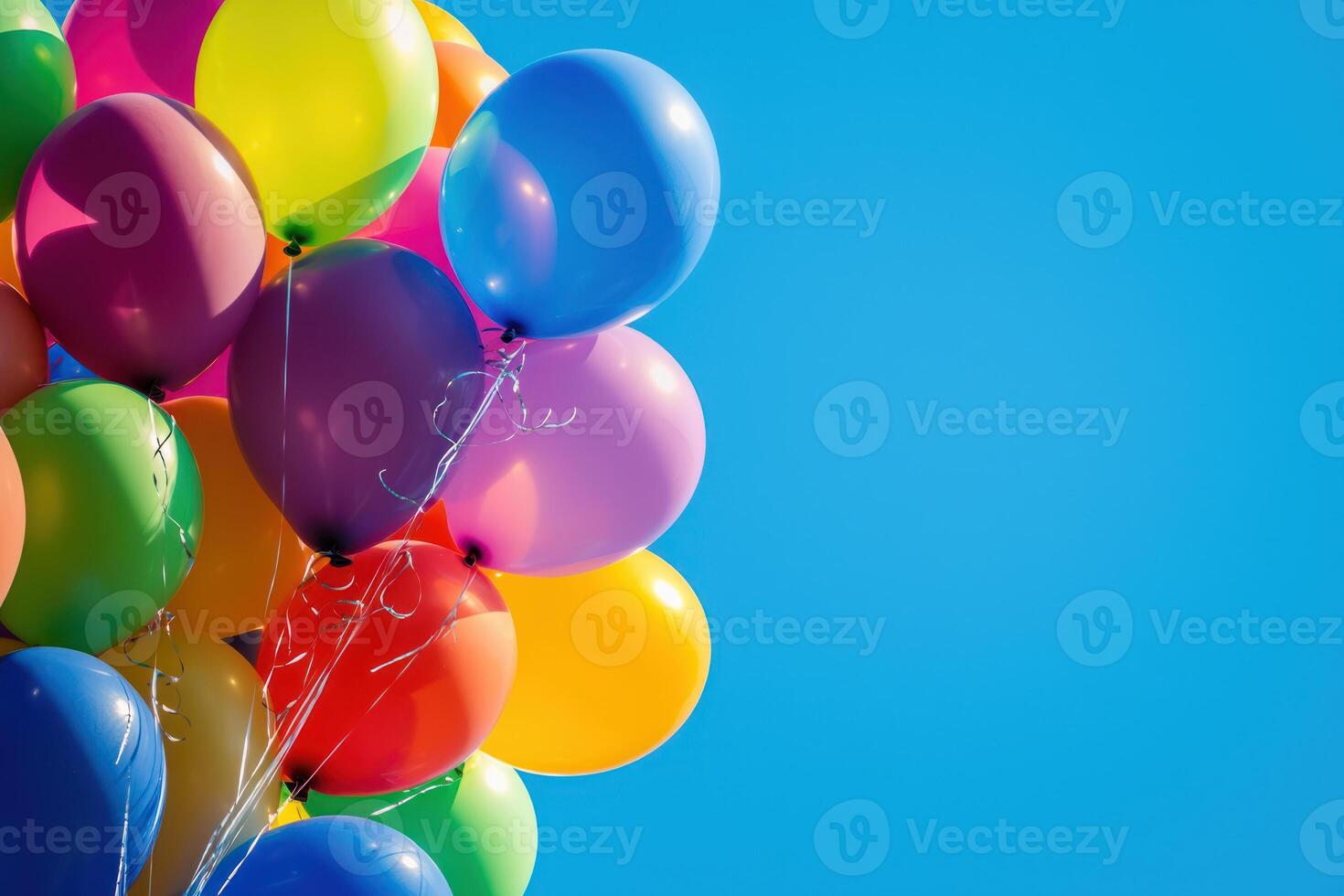 Colorful balloons floating against clear blue sky, creating festive atmosphere photo
