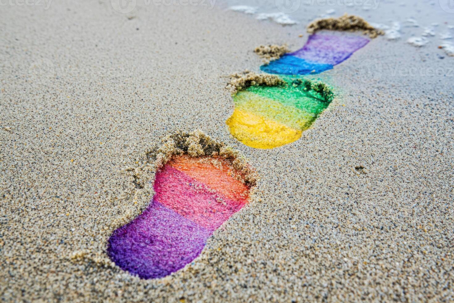 Rainbow colored footprints leading forward on sandy beach, symbolizing progress in rights activism during pride month photo