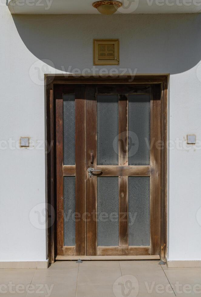 Rustic wooden door with glass panels welcomes visitors in a sunny afternoon, revealing charming architecture photo