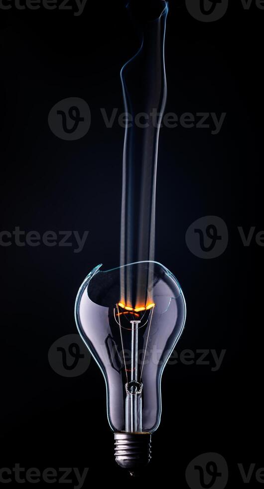 Intriguing light bulb emits glowing filament surrounded by swirling smoke in a dark backdrop photo