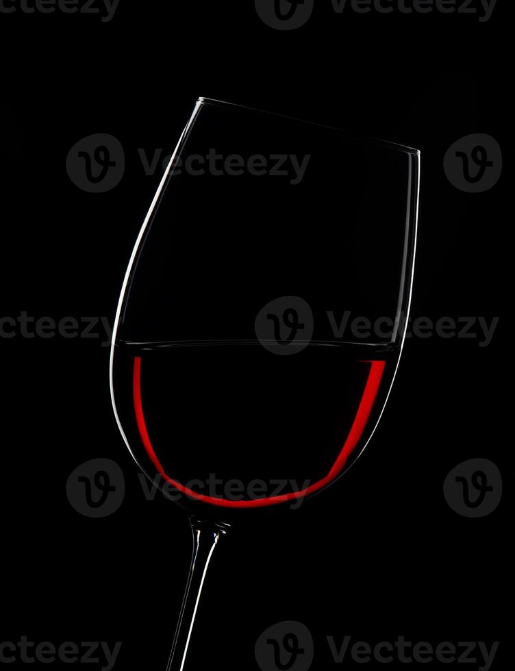 Elegant red wine glass illuminated against a dramatic black backdrop photo