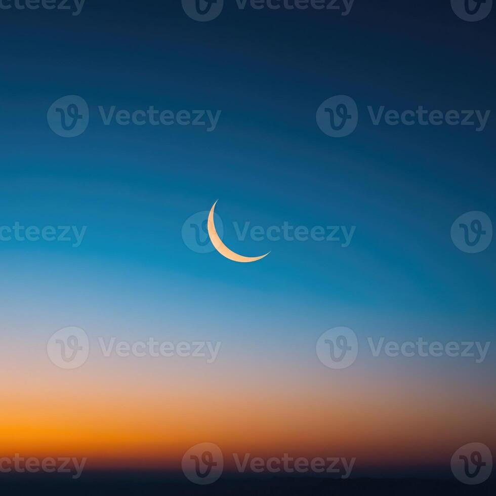 The crescent moon is seen in the sky at sunset photo