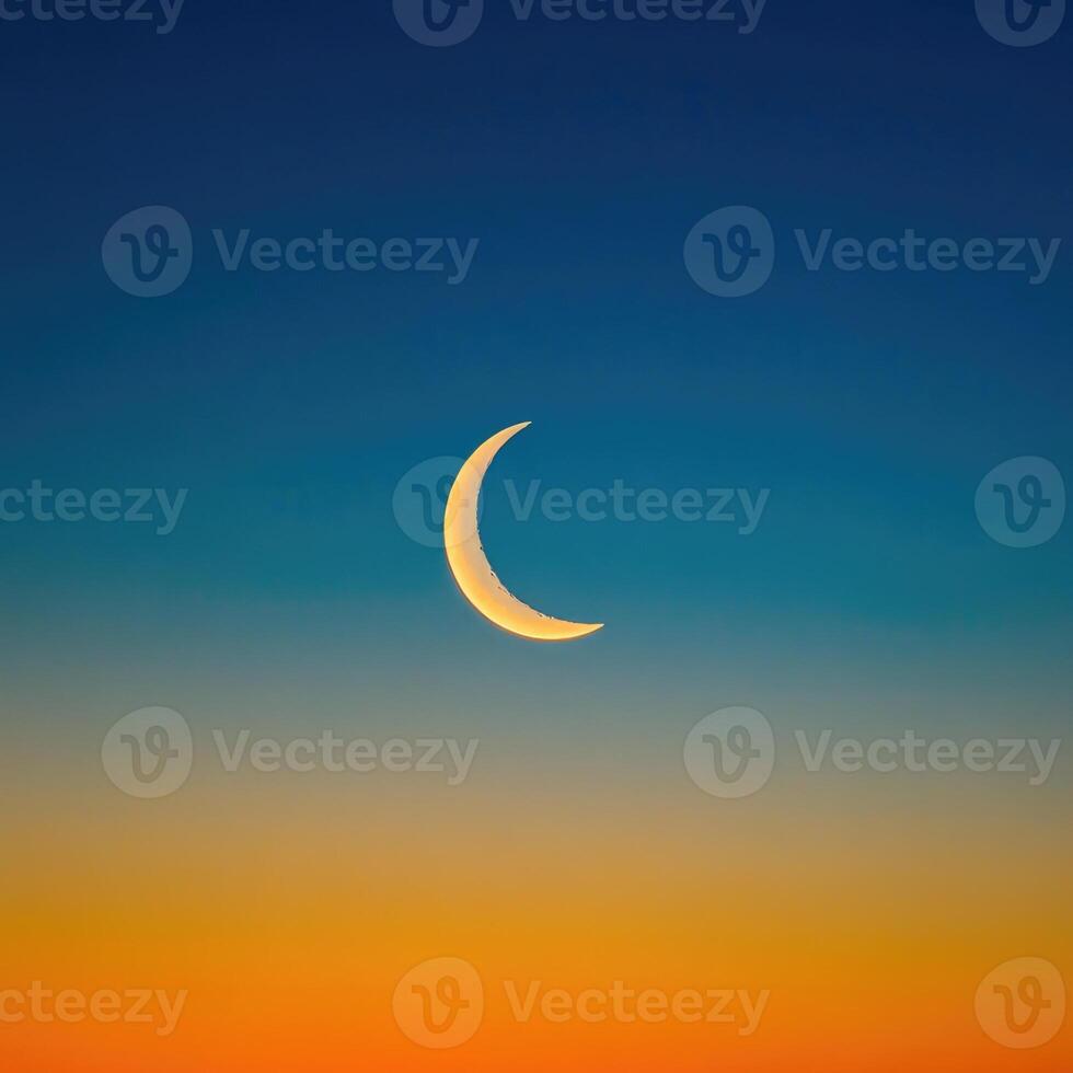 The crescent moon is seen in the sky at sunset photo