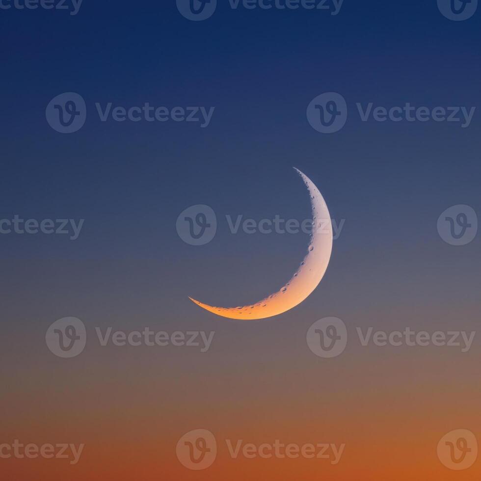 The crescent moon is seen in the sky at sunset photo