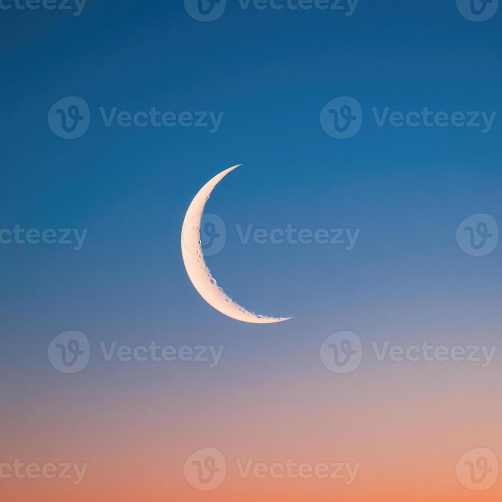 The crescent moon is seen in the sky at sunset photo