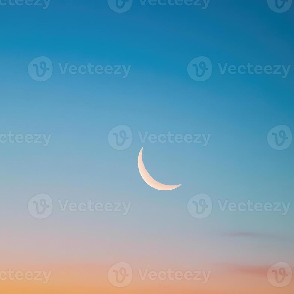 The crescent moon is seen in the sky at sunset photo