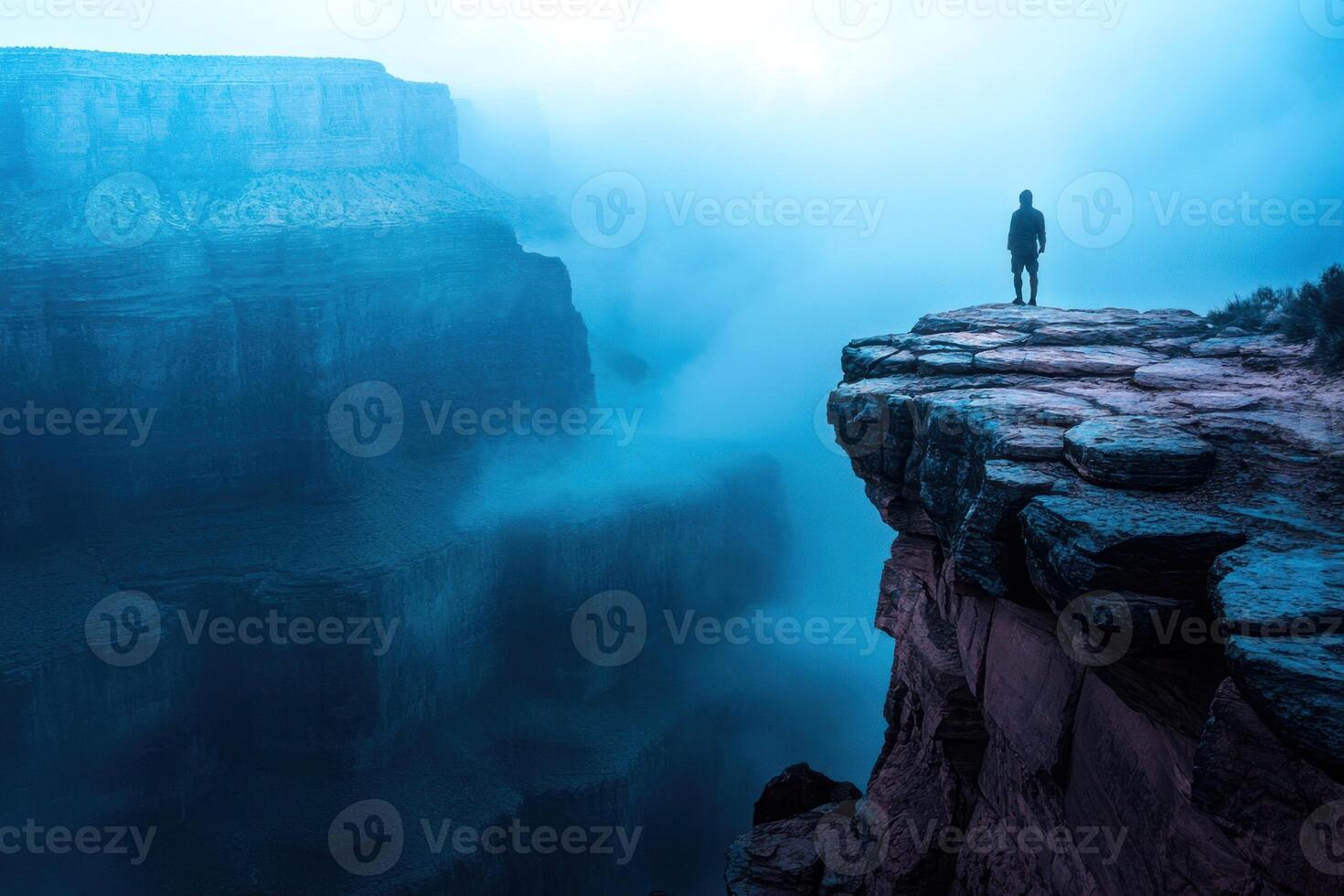 A man standing on the edge of a cliff looking at the grand canyon photo