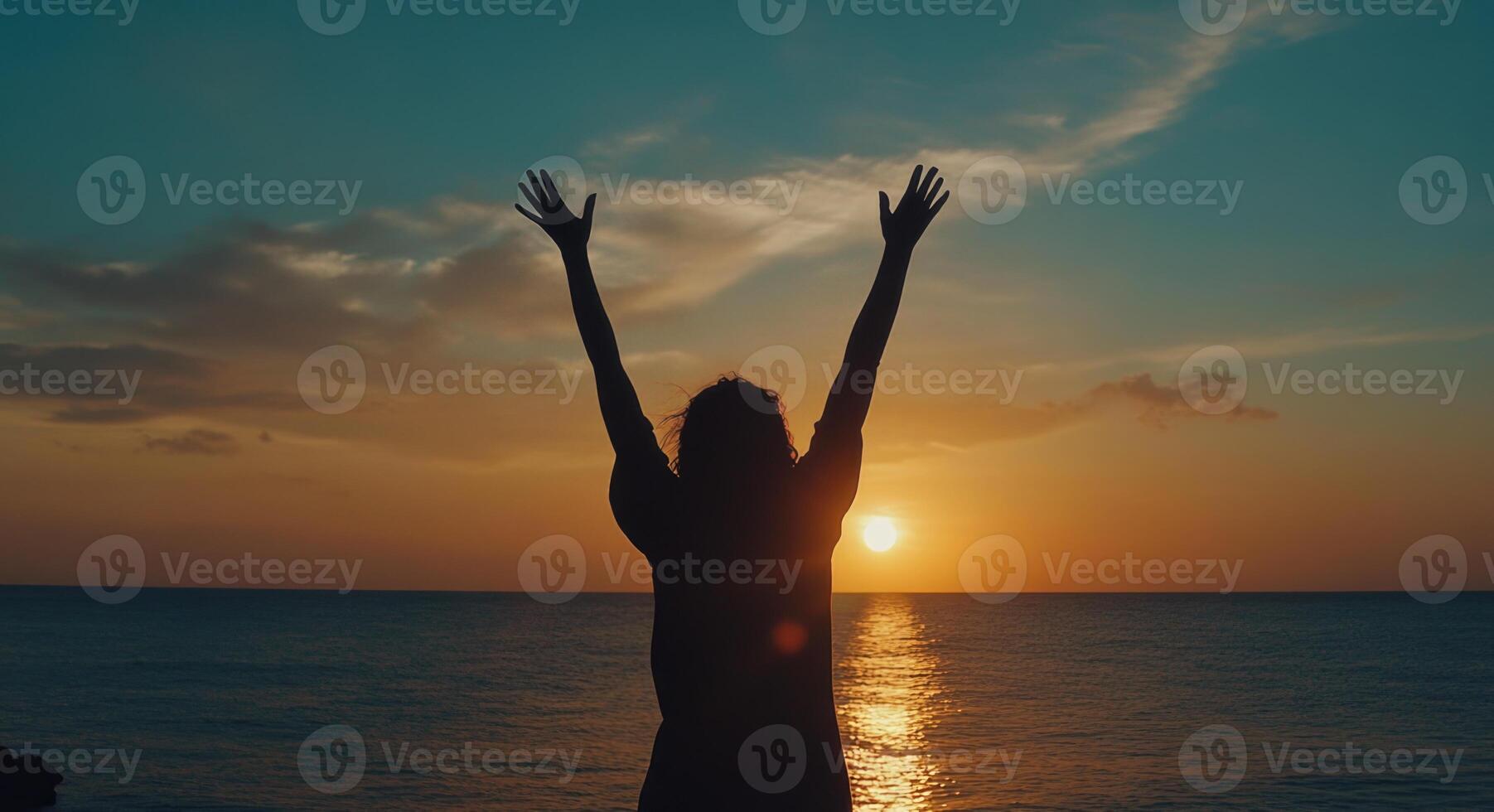 Silhouette of woman with arms raised at sunset photo