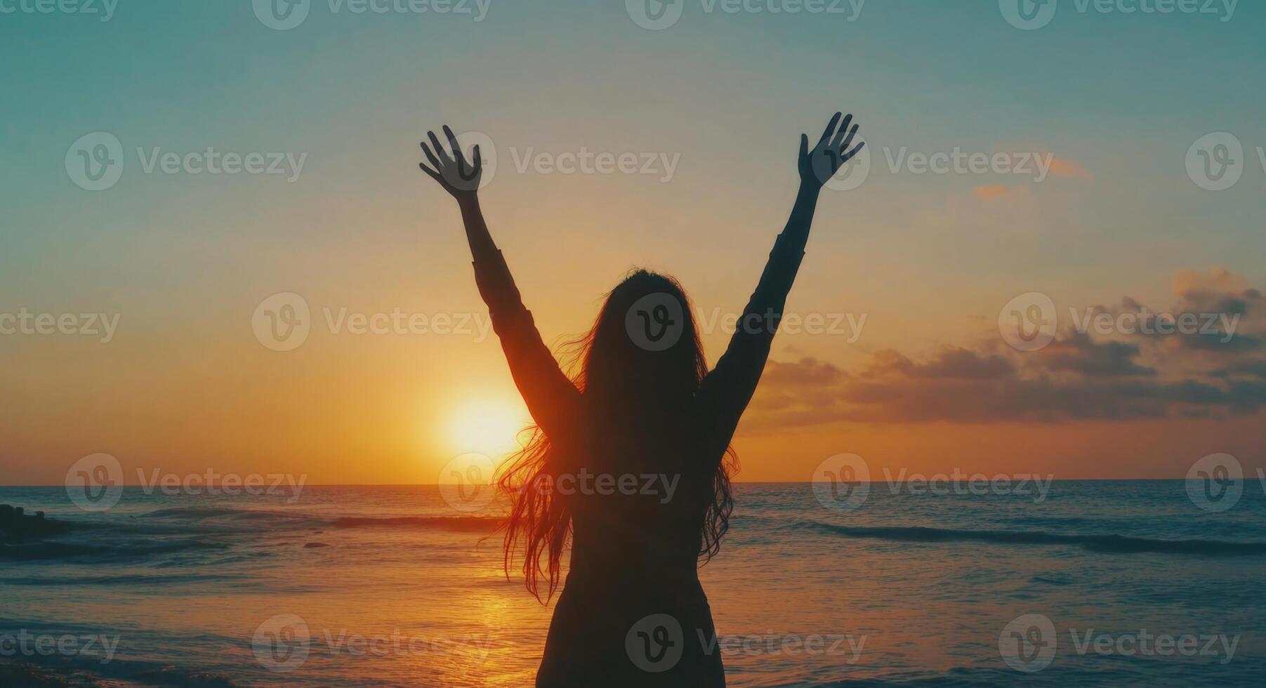 A woman with her arms up in the air at sunset photo