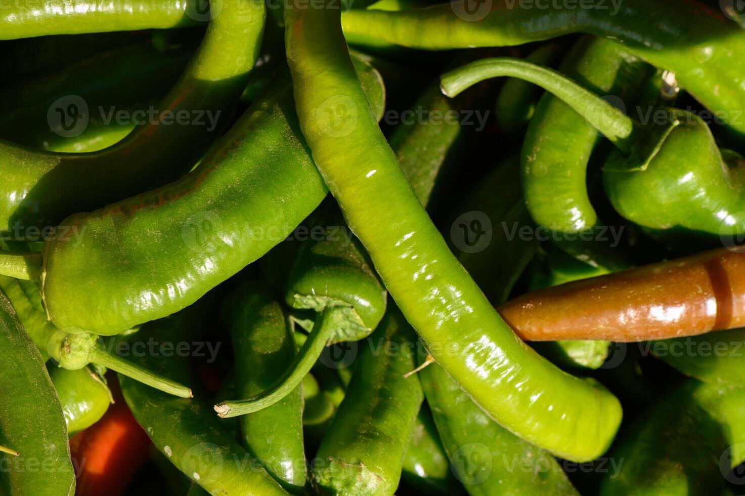 Vibrant green peppers gathered fresh from the market under warm sunlight in a bustling outdoor environment photo