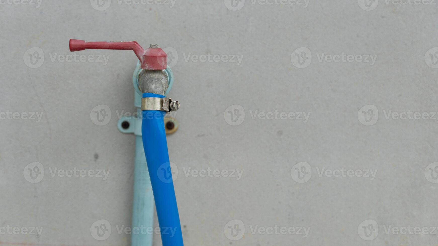 Hose clamp for water sprayer. Holds the hose from coming off the faucet. Water pipes installed on the cement wall. photo