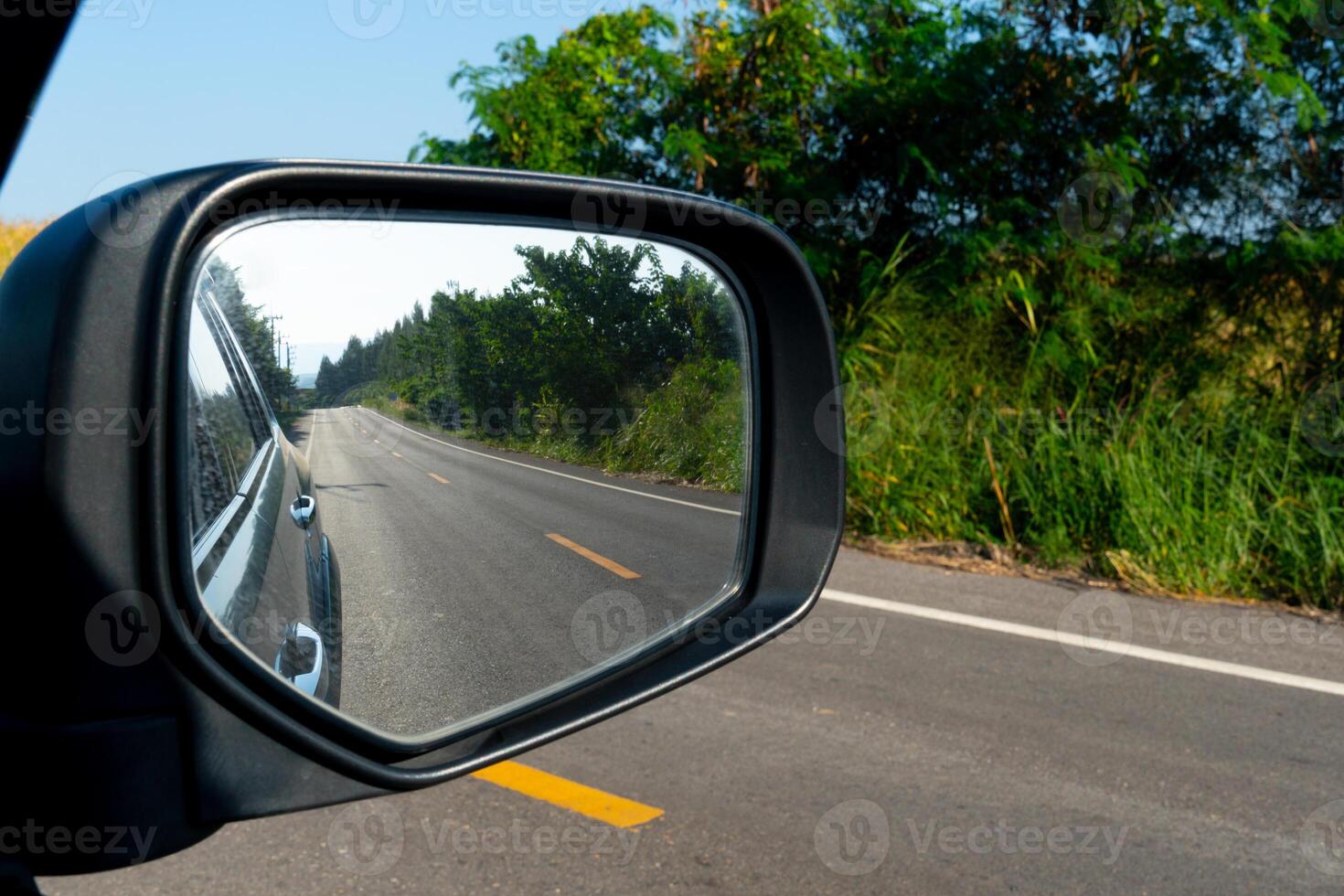 Inside view of mirrors wing. Rear view of a gray car with asphalt road. photo