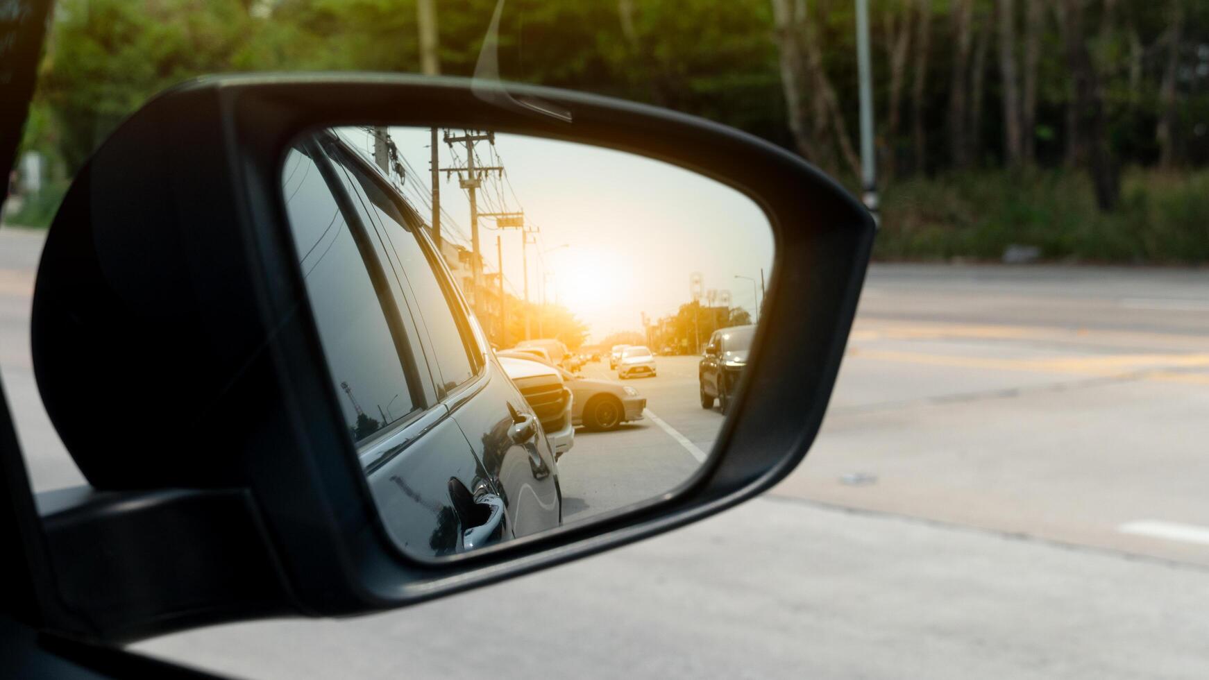 Mirror view of dark car. Reflection in the mirror of another car driving on the road with orange blur light. photo