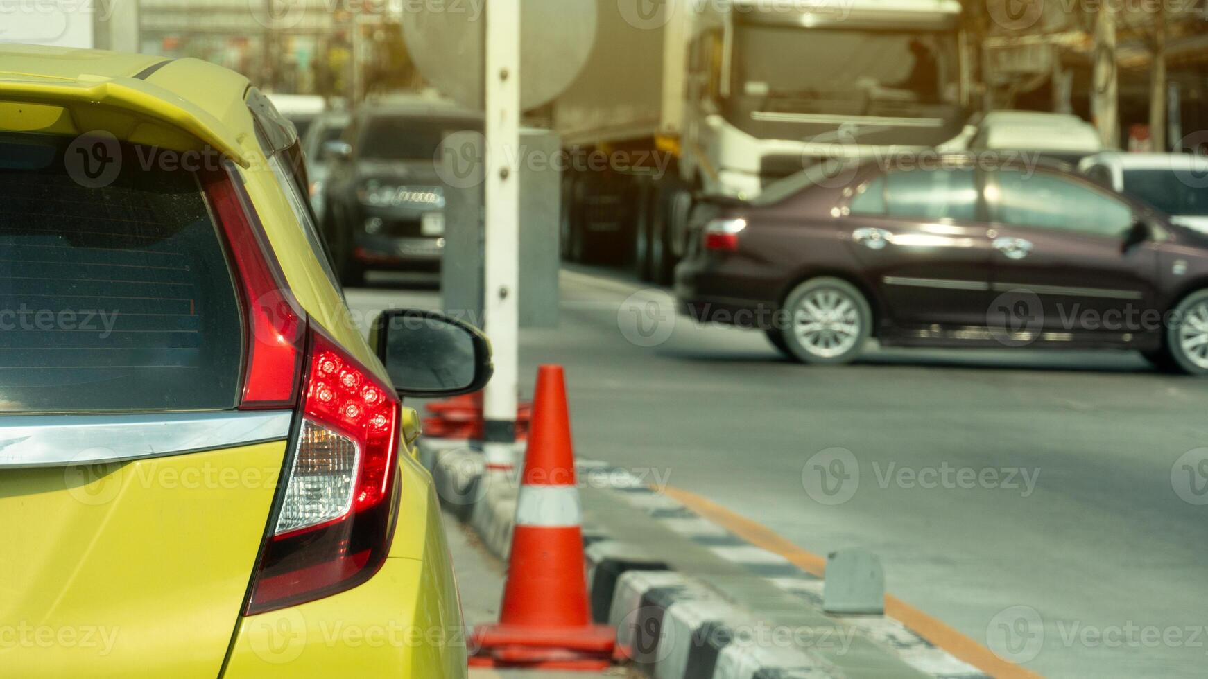 Rear side of yellow car with turn on brake light. Stop on the road waiting for traffic condition. with other car passthong in the junction. Many car stop on opposite road in the city. photo