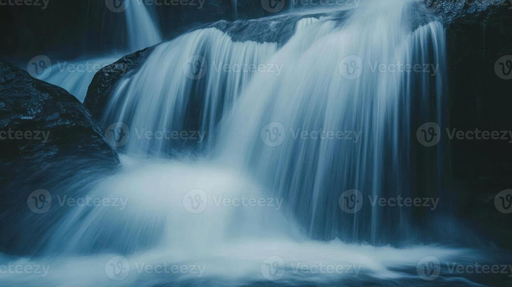 Abstract Waterfall with Smooth Blue Water Flowing over Dark Rocks photo