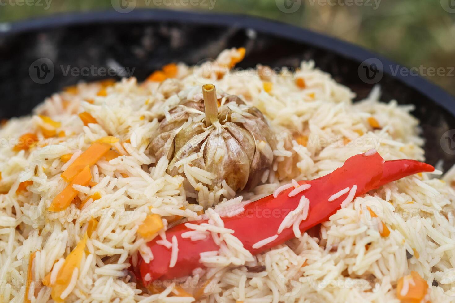 Cooking rice pilaf in a large cast-iron pot on fire photo