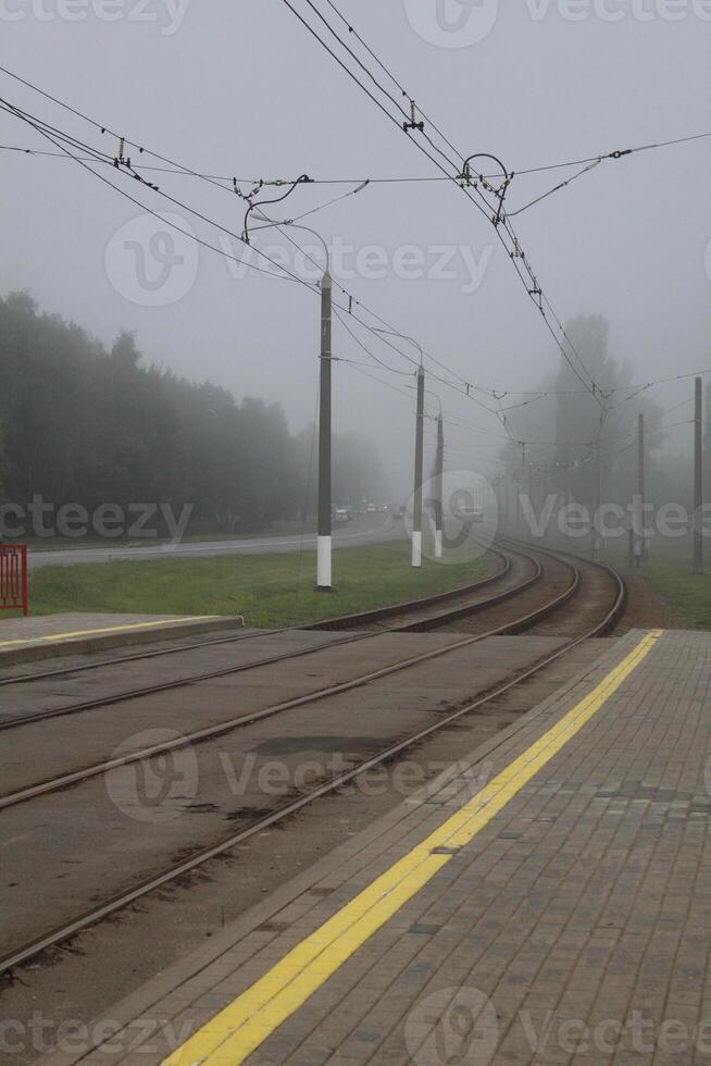 Railway, tramway, rails go into fog. Axial landscape photo