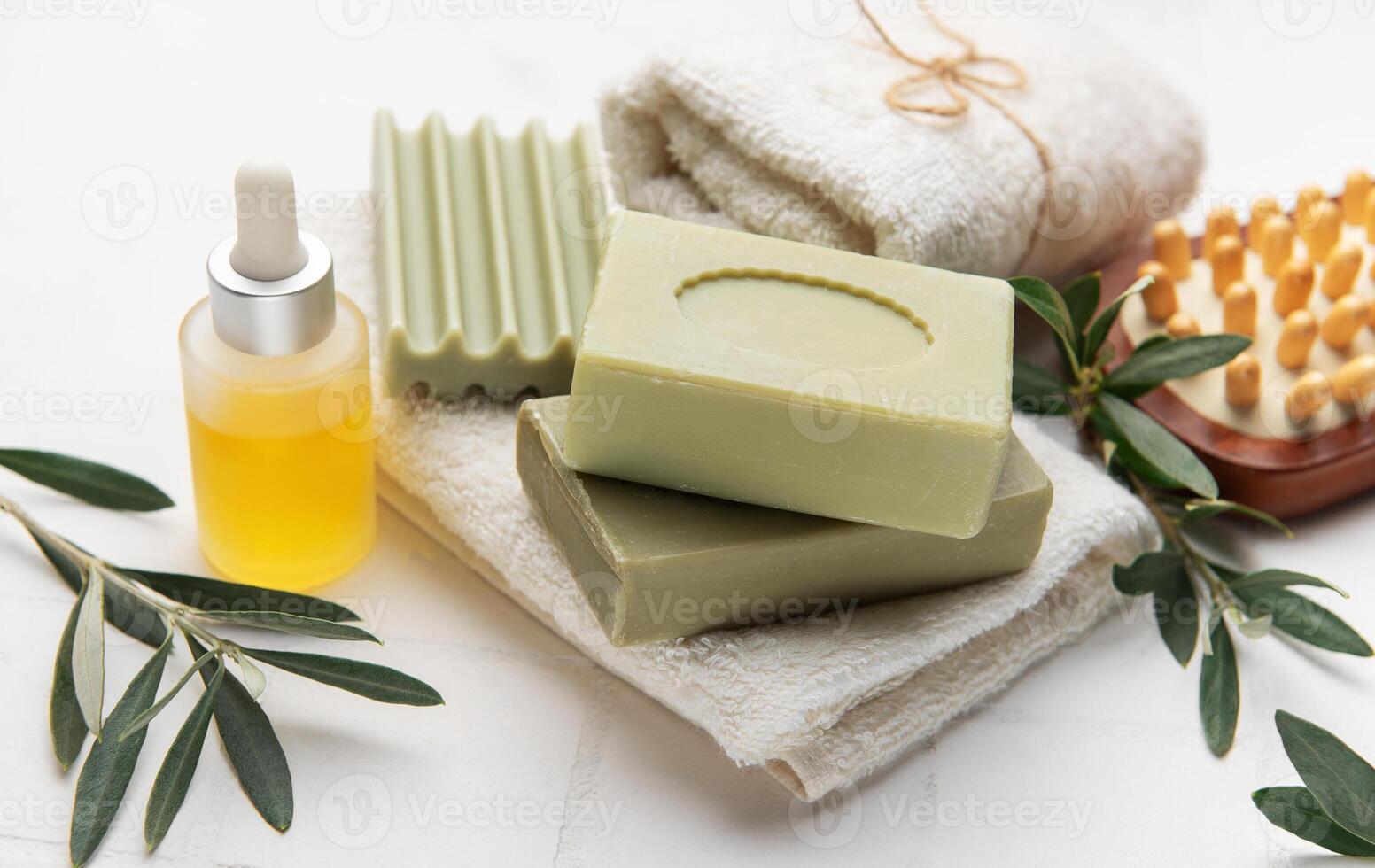 Natural olive oil soap, essential oil and white towels creating relaxing spa setting photo